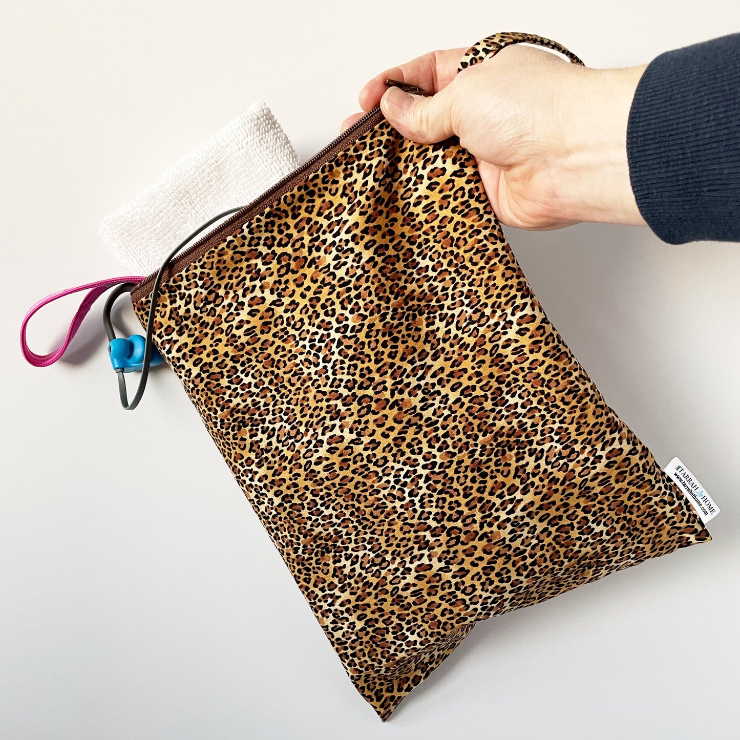 Cheetah print wetbag held by a hand on a light background