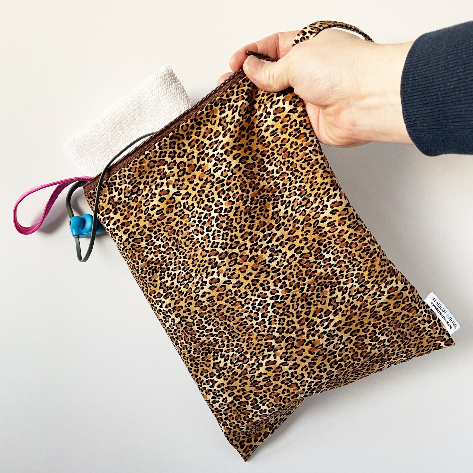 Cheetah print wetbag held by a hand on a light background